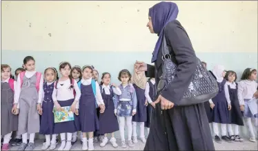  ??  ?? تلميذات يقفن احتراما لمعلمتهن في فصل بمدرسة في الجانب الأيسر من الموصل (رويترز)