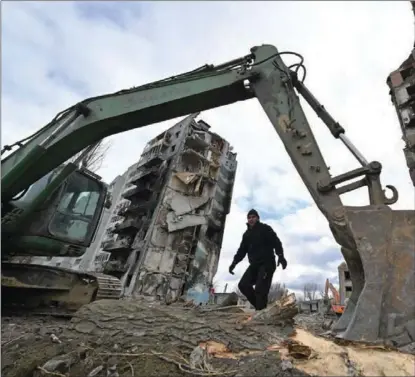  ?? SERGEI SUPINSKY / AFP ?? A digger and a communal worker clean debris on April 17 from buildings destroyed in bombardmen­t of the Ukrainian town of Borodianka, in Kyiv province.