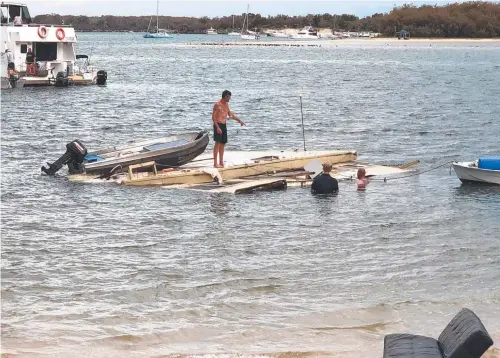  ??  ?? The owner and friends salvage what they can yesterday from the sunken houseboat in the Broadwater.