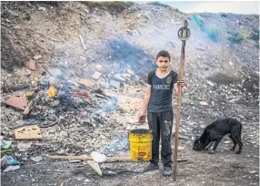  ??  ?? Maicol Vásquez with a magnet and bucket he uses to find metal to sell in Soacha, Colombia.