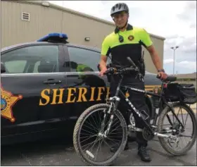  ?? RICHARD PAYERCHIN — THE MORNING JOURNAL ?? Lorain County Sheriff’s Deputy Nathaniel Krueger stands with one of the bicycles that will become part of the patrols for Sheriff Phil Stammitti’s Township Impact Unit this summer.