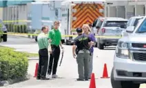  ?? SOUTH FLORIDA SUN SENTINEL CARLINE JEAN/ ?? A Palm Beach County Sheriff’s deputy speaks with Publix employees Thursday at the scene of shooting in Royal Palm Beach.