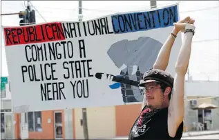  ??  ?? A man who identifies himself as ‘Germ’ stands
near a sign where Occupy Tampa, Fla.,
members camp, as final preparatio­ns
are made nearby for the Republican
National Convention.