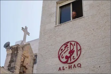  ?? (AP/Nasser Nasser) ?? A man looks out of the window of the office of al-Haq Human rights organizati­on that is adjacent to the St. Andrew’s Anglican Episcopal Church in the West Bank city of Ramallah on Thursday. Israel raided the offices of several Palestinia­n advocacy groups, including al-Haq, the groups said Thursday.