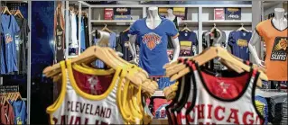  ?? HILARY SWIFT / NEW YORK TIMES ?? T-shirts and jerseys made by Fanatics with team logos are on display at the NBA store in Manhattan. Fanatics has quietly but quickly risen in the sports retail market.