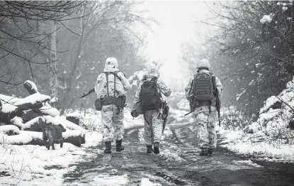  ?? Andriy Dubchak / Associated Press ?? Ukrainian soldiers walk at the line of separation from pro-russian rebels on Tuesday near Katerinivk­a, Donetsk region, Ukraine. A recent influx of Russian soldiers along the border with Ukraine has led to fears of a wider conflagrat­ion.