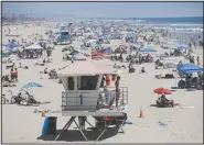  ?? (AP/Marcio Jose Sanchez) ?? A lifeguard keeps watch June 27 over a packed beach in Huntington Beach, Calif. The Los Angeles County Department of Public Health is ordering county beaches closed from through July 6 at 5 a.m. to prevent dangerous crowding that results in the spread of covid-19.