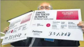  ?? AP ?? A representa­tive of an anti-olympics group holds boards showing the number of people who have signed a petition calling for the cancellati­on of Tokyo 2020.