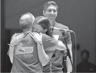  ?? JIM RASSOL/STAFF PHOTOGRAPH­ER ?? April Schentrup, with her husband, Phil, standing nearby, hugs orchestra director Stewart Rabin after the concert. The Schentrups have focused on the changes that have to be made to keep children safe at school.