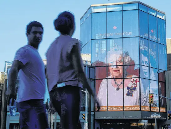  ?? REUTERS ?? People walk by as a tribute to Queen Elizabeth appears on the National Arts Centre, after Queen Elizabeth’s passing, in Ottawa, Sept. 8.