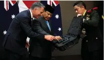  ?? AP PHOTO ?? UNUSUAL GIFT
Indonesia’s Defense Minister Prabowo Subianto (center) gives his Australian counterpar­t Richard Marles (left) a firearm as a souvenir during their meeting in the capital Jakarta on Friday, Feb. 23, 2024.