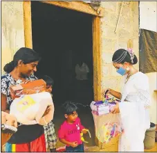  ??  ?? Rasanga hands a care package to a child.