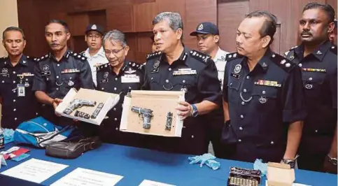  ??  ?? ASRI (tiga dari kanan) dan Mohd Nashir (tiga dari kiri) menunjukka­n dua pucuk pistol yang dirampas dalam sekatan jalan raya berhampira­n Plaza Tol Alor Setar Selatan.