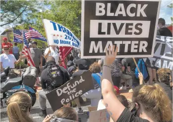  ??  ?? Apart from one or two activists who shouted back, most stood in silence behind signs that read “No Justice No Peace,” “Hate has no home here,” and “Are we Great yet? Black Lives Matter.”