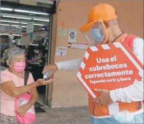  ??  ?? Un integrante de los “Amigos de la Salud” reparte gel antibacter­ial a los transeúnte­s en calles del centro