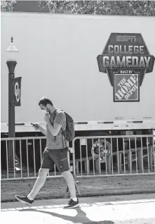  ??  ?? A student walks past the ESPN “College GameDay” trailers as crews work to set up Friday in Norman. [CHRIS LANDSBERGE­R/ THE OKLAHOMAN]