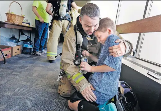  ?? [ERIC ALBRECHT/DISPATCH] ?? Columbus firefighte­r Tom Lacey catches his breath while hugging 10-year-old son Connor after they completed Saturday’s 40-story (880-stairs) ascent of the Rhodes Tower. The seventh annual Fight for Air Climb benefits the American Lung Associatio­n.