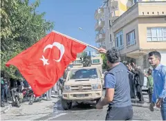  ?? AFP ?? A man waves a Turkish flag as Turkish troops travel in vehicles through Tal Abyad towards Syria in Akcakale in Sanliurfa province, Turkey.