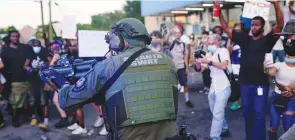  ?? (Elijah Nouvelage/Reuters) ?? AN ATLANTA SWAT officer draws his weapon in Atlanta on Saturday during a rally against racial inequality and the police shooting death of Rayshard Brooks.