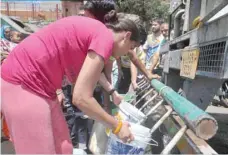  ?? — AFP ?? Residents gather to collect drinking water with buckets from a water tanker following water shortages in Shimla.