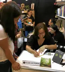  ??  ?? AUTHOR Eliza Victoria autographs her books for a fan.