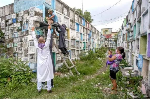  ?? AFP/VNA Photos ?? EMOTIONAL MOMENT: Corazon Enriquez (right) taking photos of workers removing the bones of her son Rodzon on July 8.