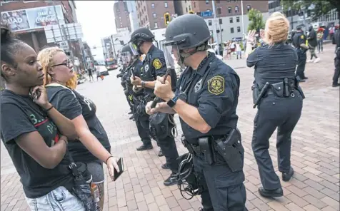  ?? Stephanie Strasburg/Post-Gazette photos ?? Nina Paige, left, 26, of Homewood, watches police create a pathway through protesters for an ambulance on Monday at Grant Street and Boulevard of the Allies. The protests were calling for justice for Antwon Rose II.