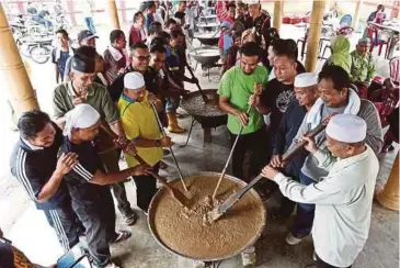  ??  ?? PENDUDUK yang terdiri daripada Majlis Pengurusan Komuniti Kampung (MPKK), Belia 4B dan ahli Jawatankua­sa masjid bergotong-royong memasak dan mengacau bubur asyura.