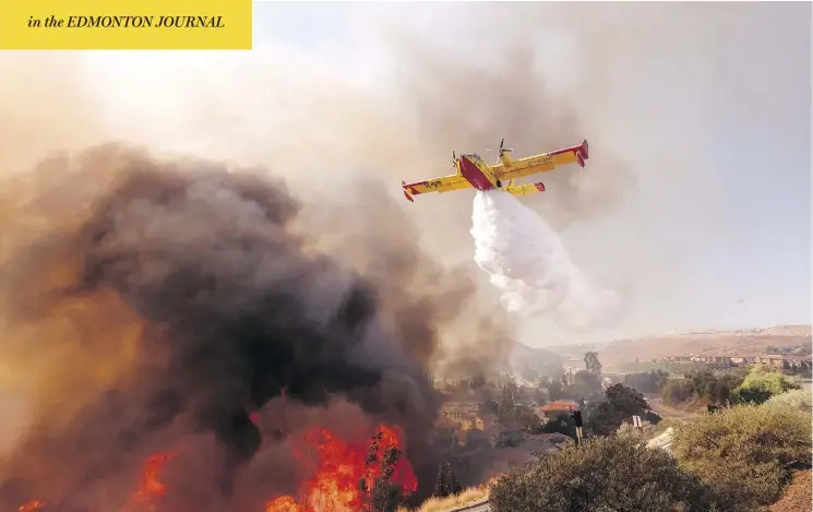  ?? RINGO H.W. CHIU / THE ASSOCIATED PRESS ?? An air tanker drops water on a fire along the Ronald Reagan Freeway in Simi Valley, Calif., on Monday. Authoritie­s in the state are searching for more than 200 missing people, some of whom are suspected to have been killed in a blaze that burned so hot that it melted metal off cars.