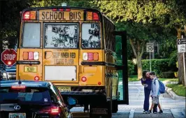  ?? RICHARD GRAULICH / THE PALM BEACH POST ?? A boy gets a kiss before he boards the bus bound for Beacon Cove Intermedia­te School on the first day of school Monday in Jupiter.