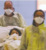  ?? SHANNON VANRAES / REUTERS FILES ?? Winnipeg paramedics dressed in protective clothing and wearing masks guide a stretcher carrying an ill woman who was on a flight from Vancouver to a waiting ambulance at the airport in Winnipeg last month.