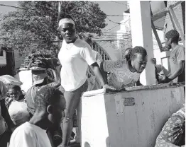  ?? ?? People look at a body after an overnight shooting in the Petion Ville neighbourh­ood of Port-au-Prince, Haiti, Monday, March 18, 2024.