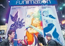  ?? Sandy Huffaker Getty Images ?? VISITORS to Comic-Con Internatio­nal in San Diego last month pass by the booth for Funimation. It releases anime through streaming, on DVD and in cinemas.