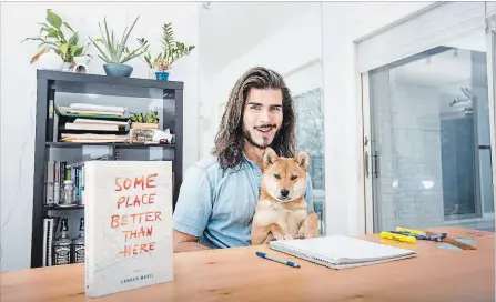  ?? BOB TYMCZYSZYN
THE ST. CATHARINES STANDARD ?? Landen Wakil in his writing space with his dog Sheba. Wakil recently published his book “Some Place Better Than Here.”