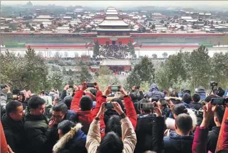  ?? DU LIANYI / CHINA DAILY ?? Visitors photograph the snowy scene at the Forbidden City from Jingshan Park in Beijing on Tuesday.