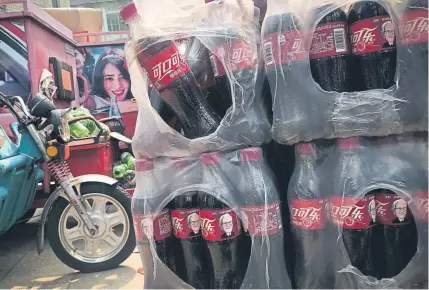  ?? Andy Wong, The Associated Press ?? Bottles of Cherry CocaCola featuring portraits of Omahabased Berkshire Hathaway chairman and CEO Warren Buffett are stacked near a dispatch rider’s bike in Beijing on Tuesday. China on Monday promised retaliatio­n if President Donald Trump escalates the U.S.China tariff battle, raising the risk that Beijing might target operations of American companies as it runs out of imports for penalties.