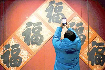  ??  ?? A man uses a snartphone to take a picture of the Chinese character ‘fu’, which means good fortune, during an exhibition for the upcoming Lunar New Year at the Palace Museum in the Forbidden City, in Beijing. — AFP photo