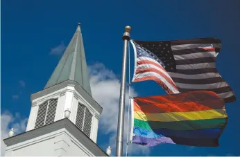  ?? AP FILE PHOTO ?? A gay pride rainbow flag flies along with the U.S. flag in front of the Asbury United Methodist Church in Prairie Village, Kan. in April.