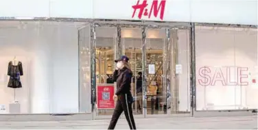  ?? File/agence France-presse ?? ↑
A woman walks past an outlet of H&M at a shopping mall in Beijing.