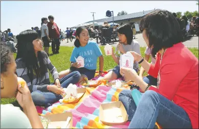  ?? NEWS-SENTINEL PHOTOGRAPH­S BY BEA AHBECK ?? Courtney Nguyen, 10, Zoe Bertsch, 11, Nadya Truong, 11, and Zoe’s mom Alisonn Wong enjoy their lunches on the grass as Lodi Unified School District debuts its new food truck at Elkhorn Elementary in Stockton on Wednesday.