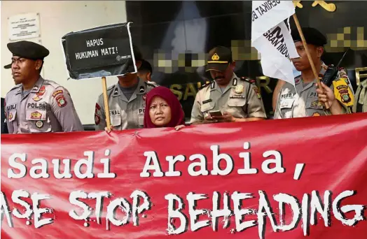  ??  ?? Making a stand An activist holding up a placard that reads ‘ Stop the Death Penalty’ as police keep watch in front of the Saudi Arabia embassy in Jakarta. The protest was related to the recent execution of an Indonesian migrant worker for murder. —...