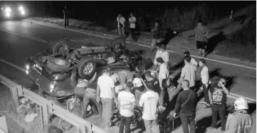  ??  ?? A crowd gathers at the scene as firemen work to extricate the trapped male victim from the overturned pickup truck.