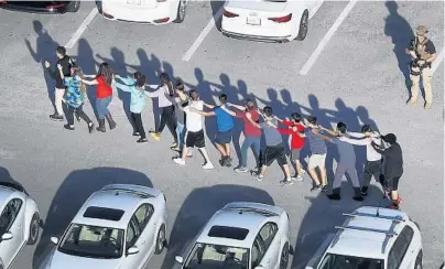  ?? JOE RAEDLE/GETTY ?? Students walk out of Marjory Stoneman Douglas High School after a shooting at the school on Feb. 14, 2018, in Parkland.