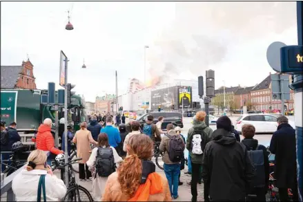  ?? ?? People watch as fire and smoke rise out of the Old Stock Exchange, Boersen, in Copenhagen, Denmark, Tuesday, April 16, 2024. (AP)