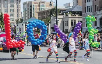  ??  ?? Members of the Times Colonist float team make their way along Government Street during the Victoria Pride Parade on Sunday.
