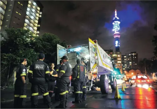  ?? PICTURES: ANTOINE DE RAS ?? READY AND WAITING: Paramedics and doctors stand together outside a makeshift hospital near Hillbrow police station in anticipati­on of any medical callouts in the area on New Year’s Eve.