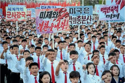  ?? PHOTOS: REUTERS ?? Young North Koreans take part in an anti-United States rally at Kim Il-sung Square in Pyongyang this week, with placards reading ‘‘Be through with the US’’, ‘‘The US is evil’s headquarte­rs’’ and ‘‘Old foe the US’’.