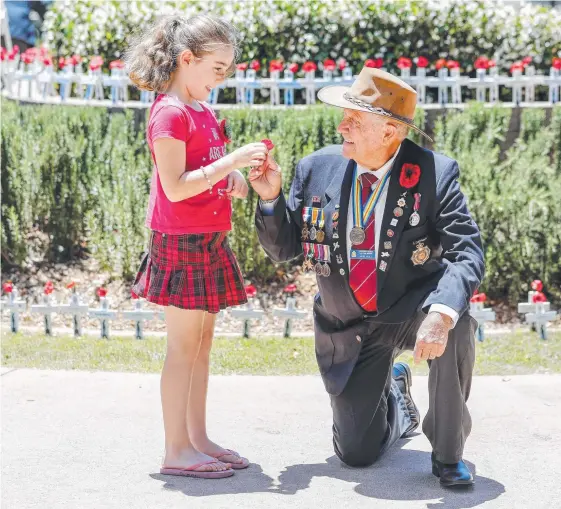  ?? Picture: TIM MARSDEN ?? Varsity College student Summer Wookey, 8, presents Noel Hull with a poppy at the Remembranc­e Day ceremony at Burleigh Heads yesterday.
