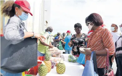  ?? PHOTOGRAPH­ER IAN ALLEN/ ?? Corporate Area residents shop at a farmers’ market held at the National Stadium car park on May 7.