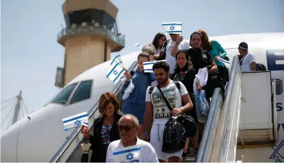  ?? (Ronen Zvulun/Reuters) ?? NEWLY ARRIVED Jewish immigrants from France wave Israeli flags upon their arrival in Israel on a special flight organized by the Jewish Agency for Israel at Ben-Gurion Airport.